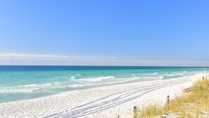 A beach with white sand and clear blue water. - Aegean 314 (Destin)