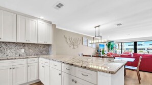 A modern kitchen with white cabinets, granite countertops, and a central island. - Aegean 314 (Destin)