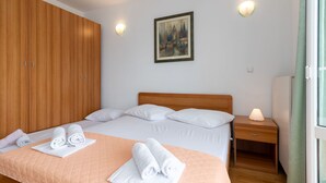 A neatly made bed with white linens, a wooden wardrobe, a painting on the wall, and a bedside lamp. - Jerkan 17 by Interhome (Podstrana)