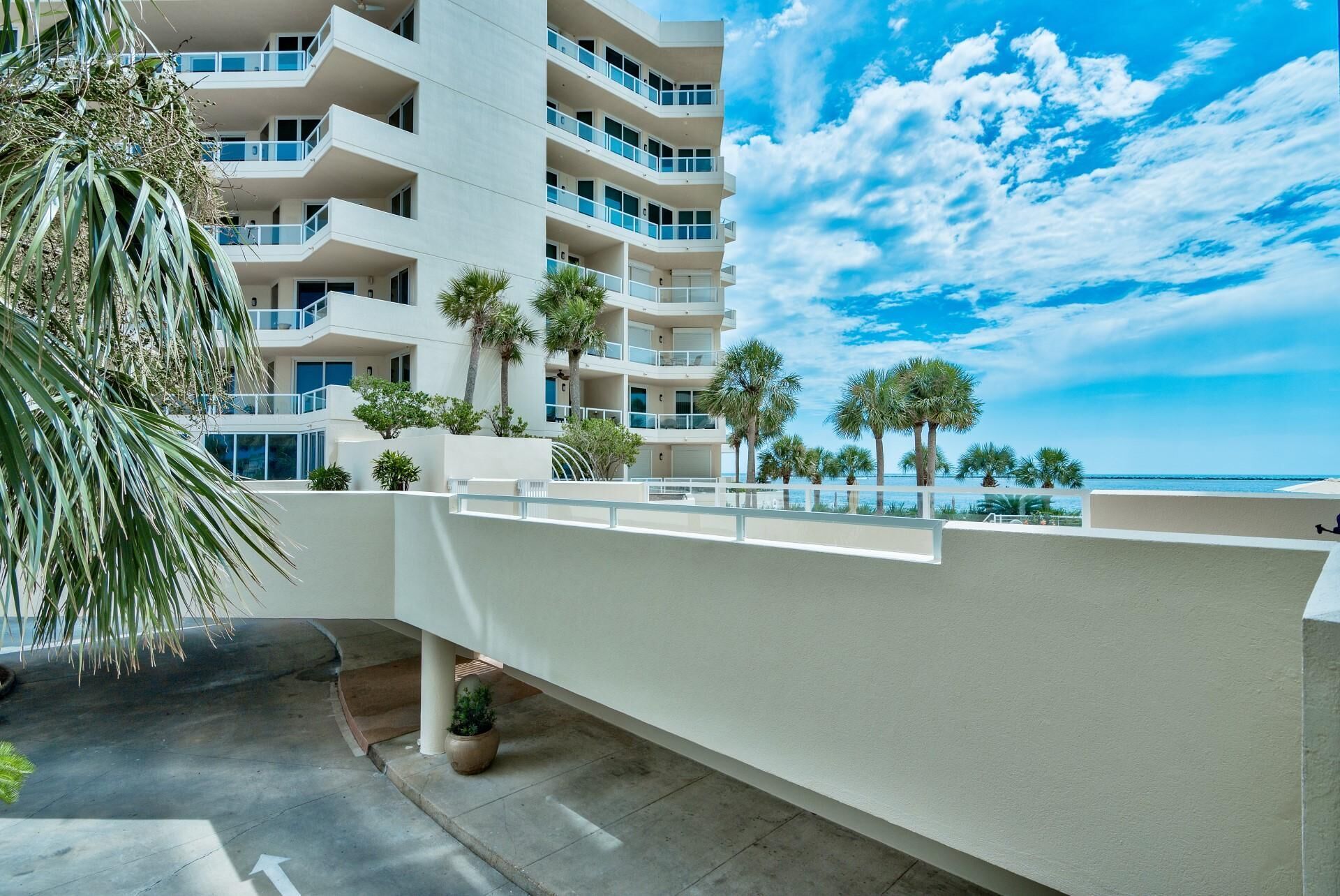 A multi-story hotel with balconies, palm trees, and a view of the ocean.
