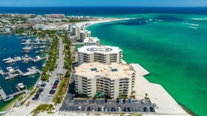 A coastal hotel with multiple floors, a marina with boats, and a beach in the background. - East Pass Towers 111 (Destin)