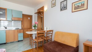 Ett kompakt bostadsutrymme med ett litet kök, en matplats och en soffa.