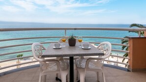 Une table avec deux chaises sur un balcon donnant sur la mer.