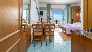 Ett kompakt hotellrum med en matplats, en säng och utsikt över havet.