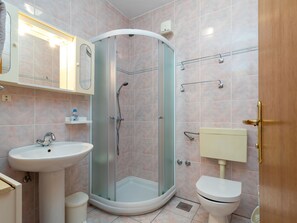 A bathroom with a glass-enclosed shower, a sink, a toilet, and a mirror. - Jerkan 13 by Interhome (Podstrana)