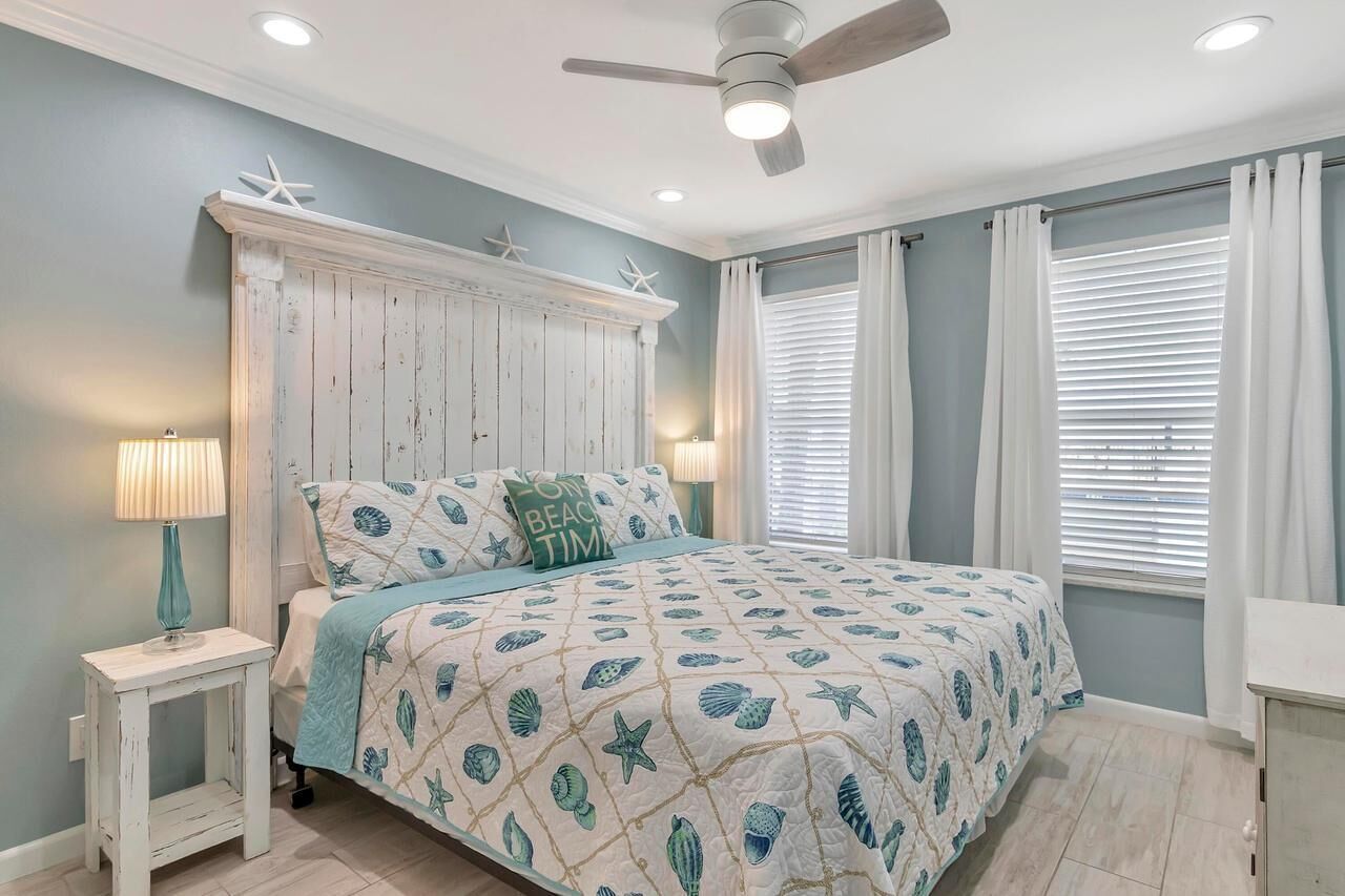 A bedroom with a bed, a nightstand, a ceiling fan, and a window with blinds.