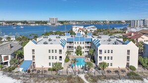 A beachfront hotel with a swimming pool, multiple balconies, and a view of the ocean and marina. - Poolside Villas 106 (Destin)