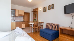 A hotel room with a bed, a sofa, a dining table with chairs, a kitchen area, and a TV. - Jerkan 12 by Interhome (Podstrana)