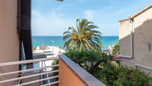 A balcony with a view of the sea, a palm tree, and a building facade. - Jerkan 11 by Interhome (Podstrana)
