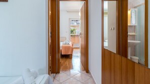 A hallway leading to a bedroom with a bed, a bathroom with a sink and mirror, and a balcony with plants. - Jerkan 11 by Interhome (Podstrana)