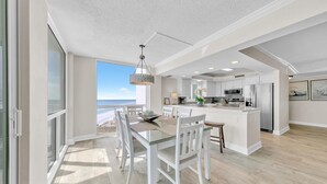 A spacious kitchen with modern appliances, a dining area with a view of the ocean, and a large island with seating. - Shoreline Towers 1061 (Destin)