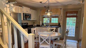 A kitchen with white cabinets, a dining table with chairs, and a staircase. - Relax and enjoy this Country Charm! (Galena)