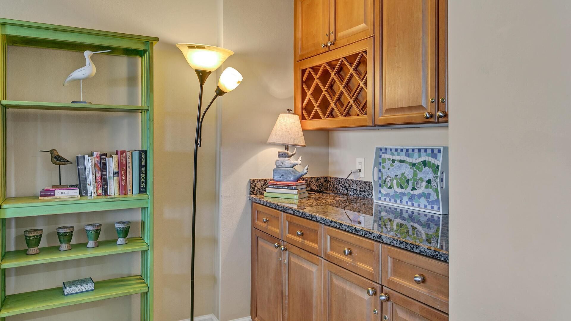 A kitchen with green shelves, wooden cabinets, a marble countertop, and a mosaic tile backsplash.