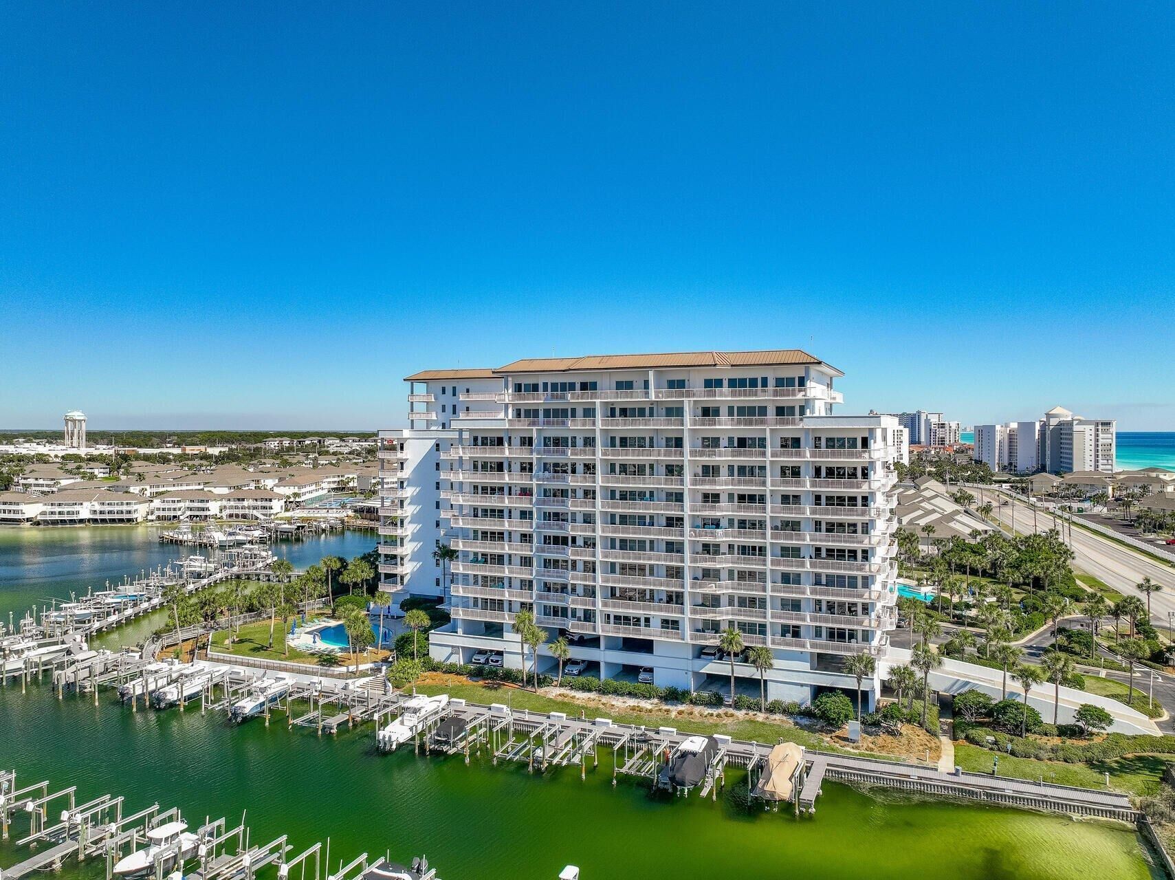 Un hôtel à plusieurs étages doté de balcons, une marina avec des bateaux et une vue dégagée sur l’océan.