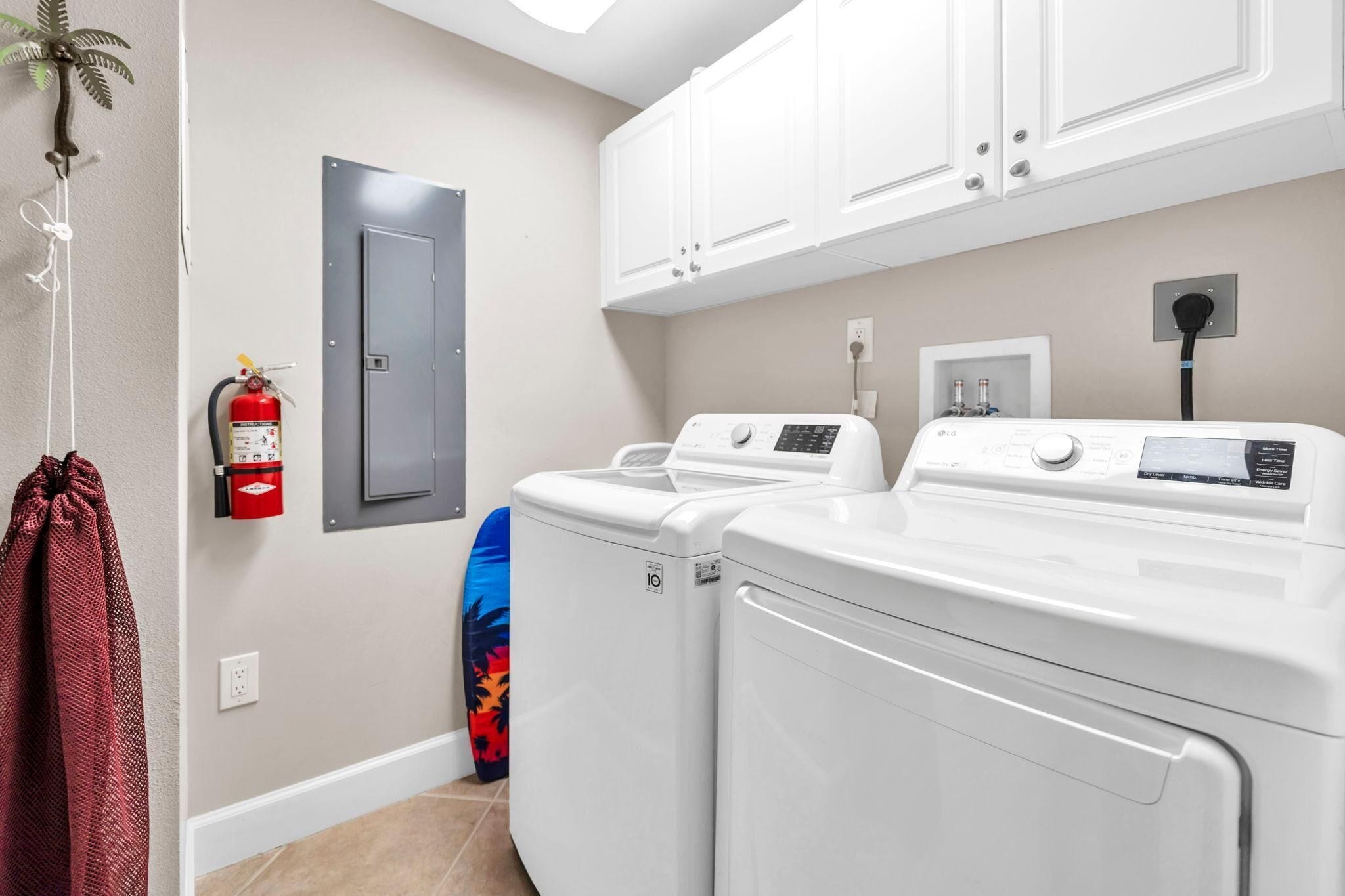 A laundry area with two front-loading washing machines, a fire extinguisher, and a door.