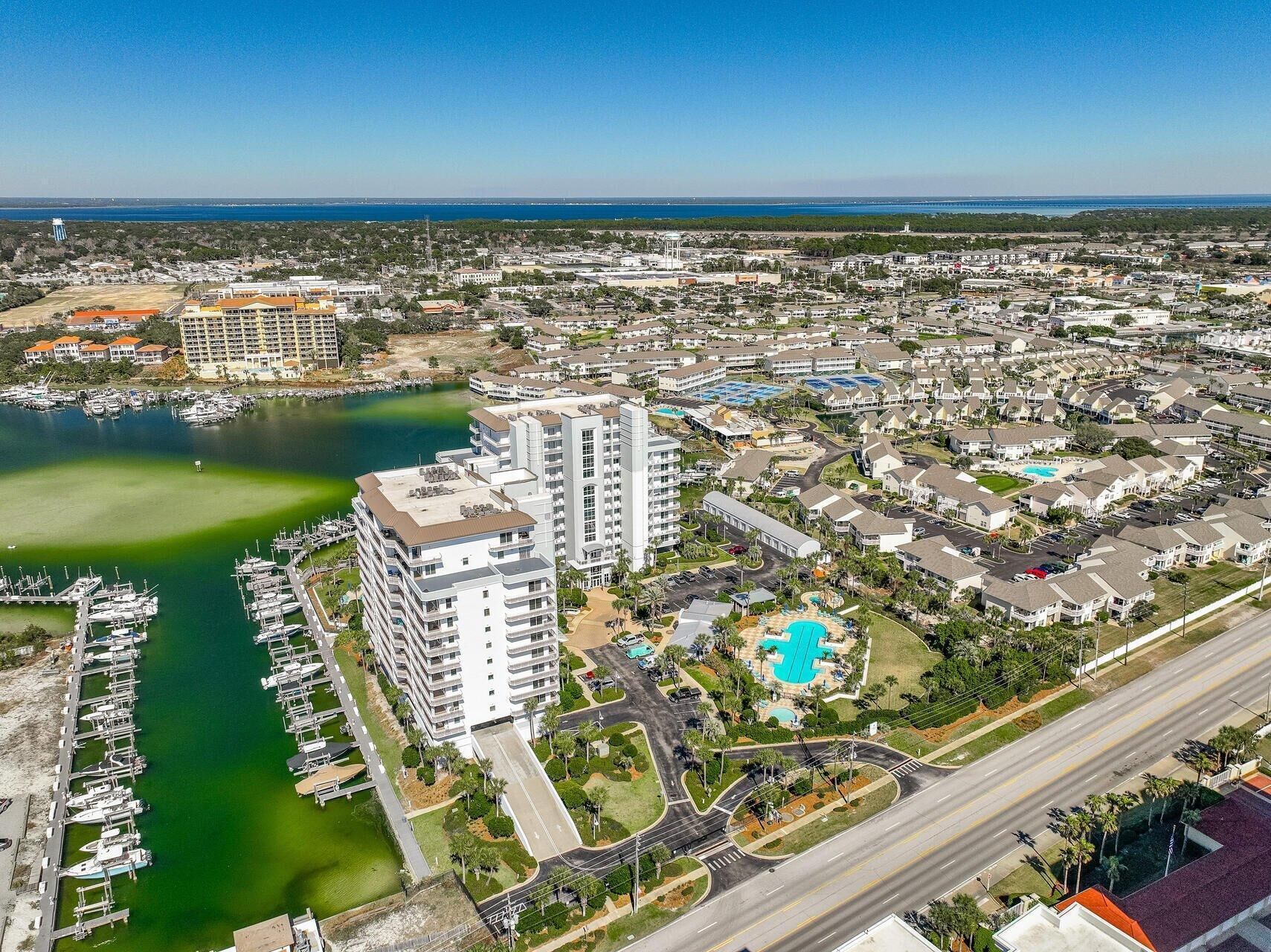 A coastal residential area with a marina, a large hotel with multiple floors, and a swimming pool complex.