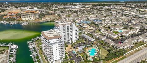 A coastal residential area with a marina, a large hotel with multiple floors, and a swimming pool complex.