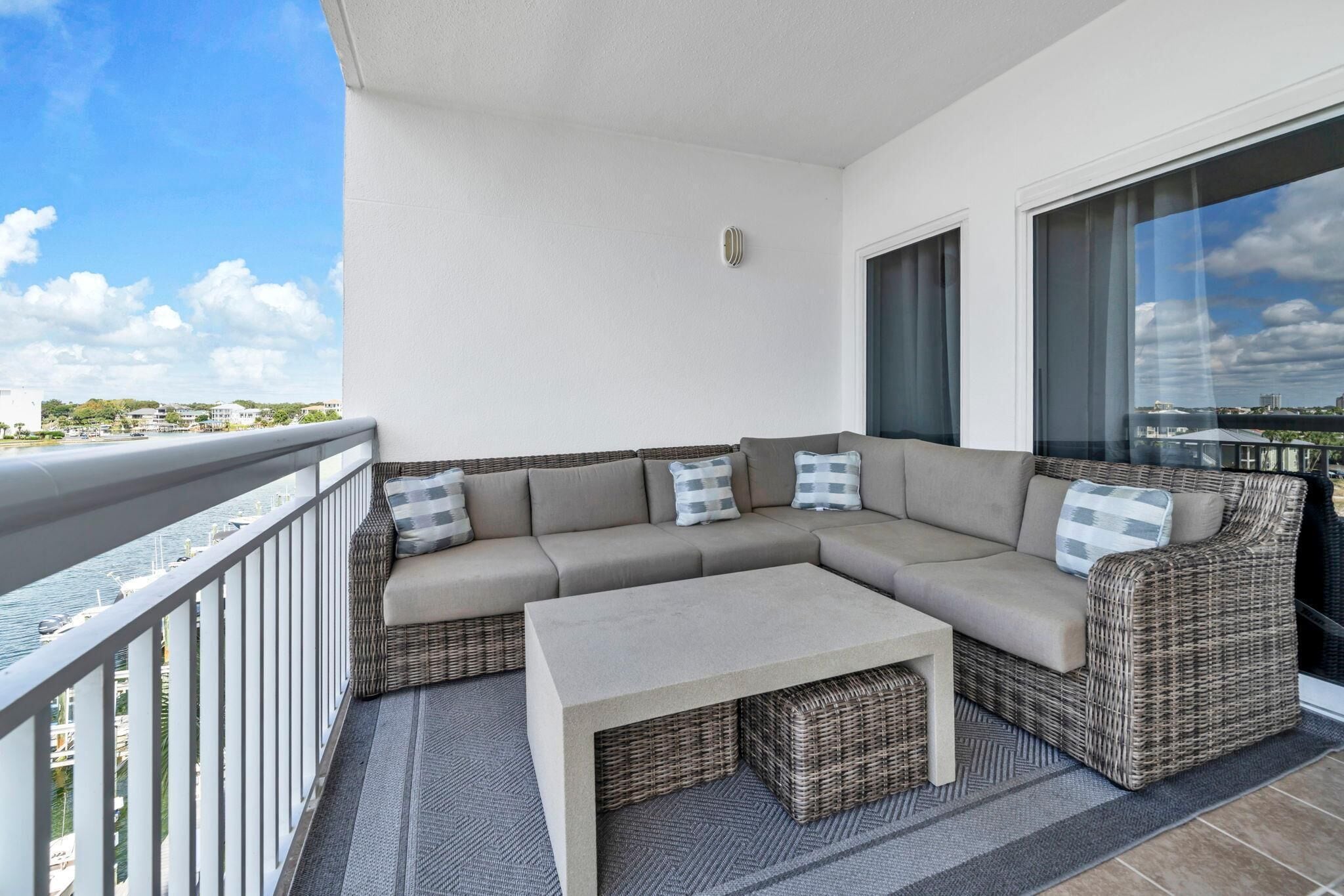 A balcony with a beige sectional sofa, a small table, and wicker baskets.