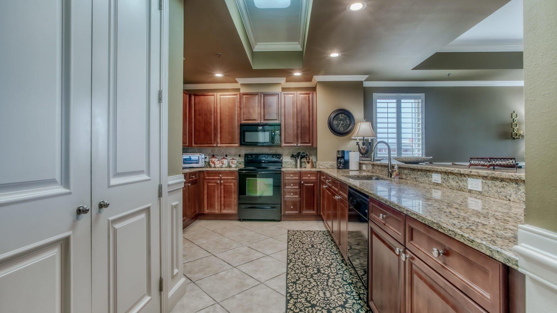 A kitchen with wooden cabinets, a microwave, stove, and a sink.