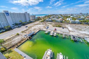 Un port de plaisance avec des bateaux amarrés, un hôtel appelé « OCEANIA » qui compte plusieurs étages, et une plage en arrière-plan.