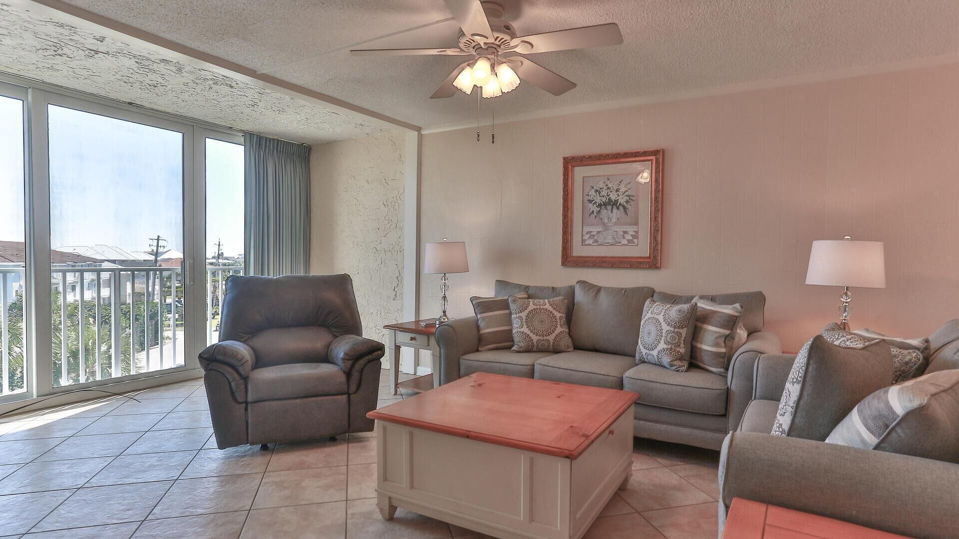 A living room with a ceiling fan, a sofa set, a coffee table, and a chair.