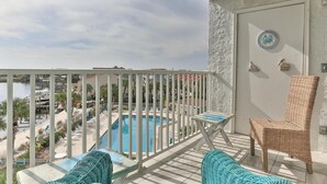 A balcony with a view of a swimming pool, wicker furniture, and decorative wall items. - Dolphin Point 402c (Destin)