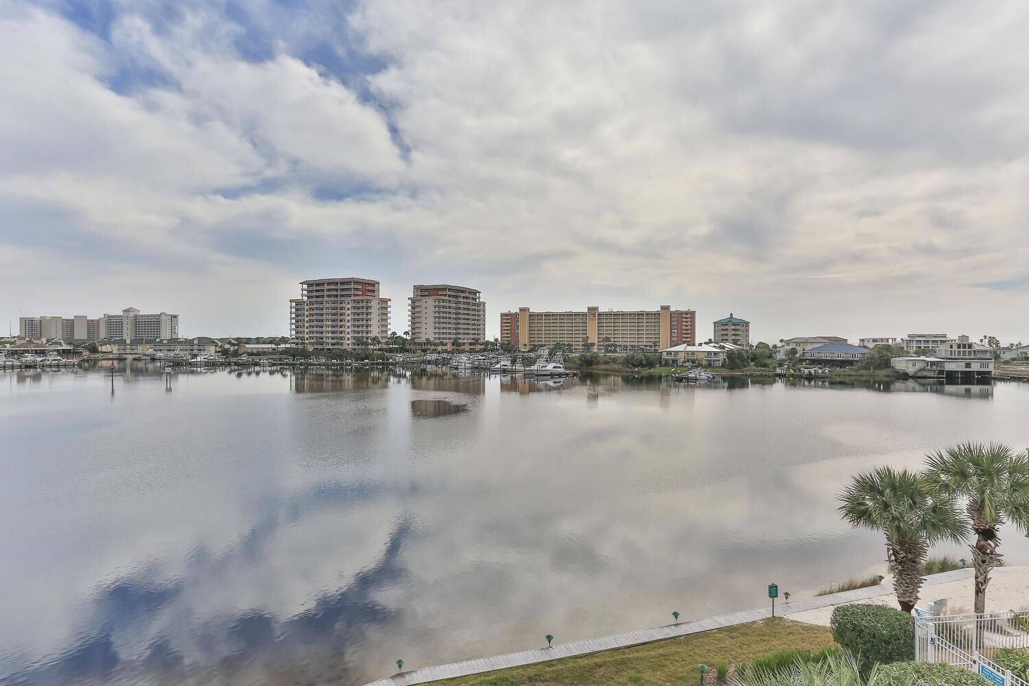 A marina with boats, a waterfront promenade, and several high-rise hotels in the background.