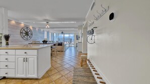A modern kitchen with white cabinetry, a large island, and a view to the outside. - Dolphin Point 502b (Destin)