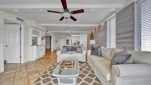 A spacious living room with a ceiling fan, a dining area, and a kitchen in the background. - Dolphin Point 502b (Destin)