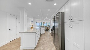 Une cuisine moderne avec des meubles blancs, un îlot central et un réfrigérateur en acier inoxydable.