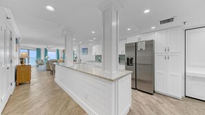 Une cuisine spacieuse avec des meubles blancs, un grand îlot central et des appareils électroménagers en acier inoxydable.