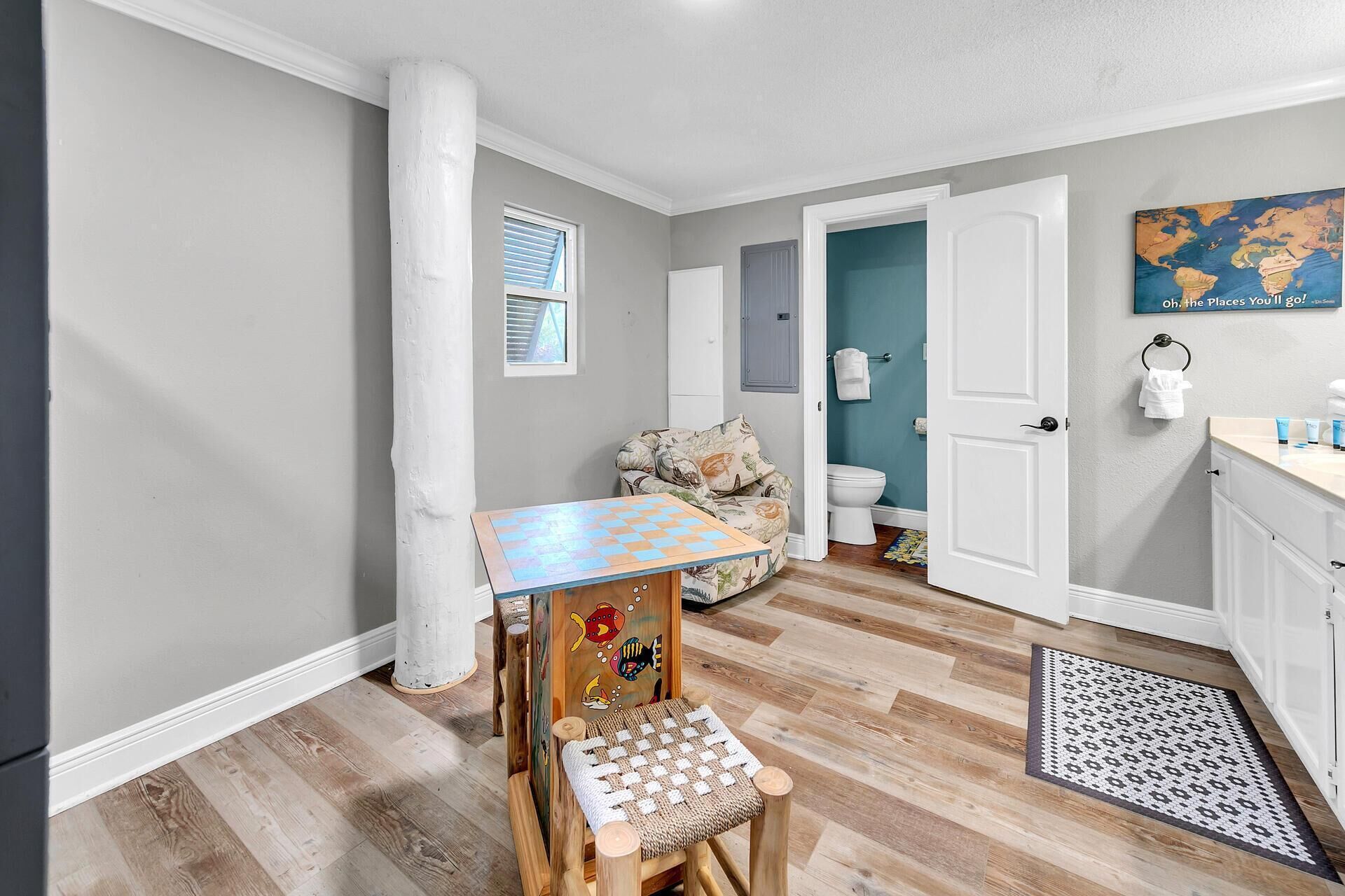 A compact living space with a dining table, a sofa, a small play area, and a bathroom.