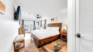 Ein Schlafzimmer mit einem hölzernen Bett, einem Deckenventilator, einem an der Wand befestigten Fernseher und einem Schild mit der Aufschrift 'RELAX'.