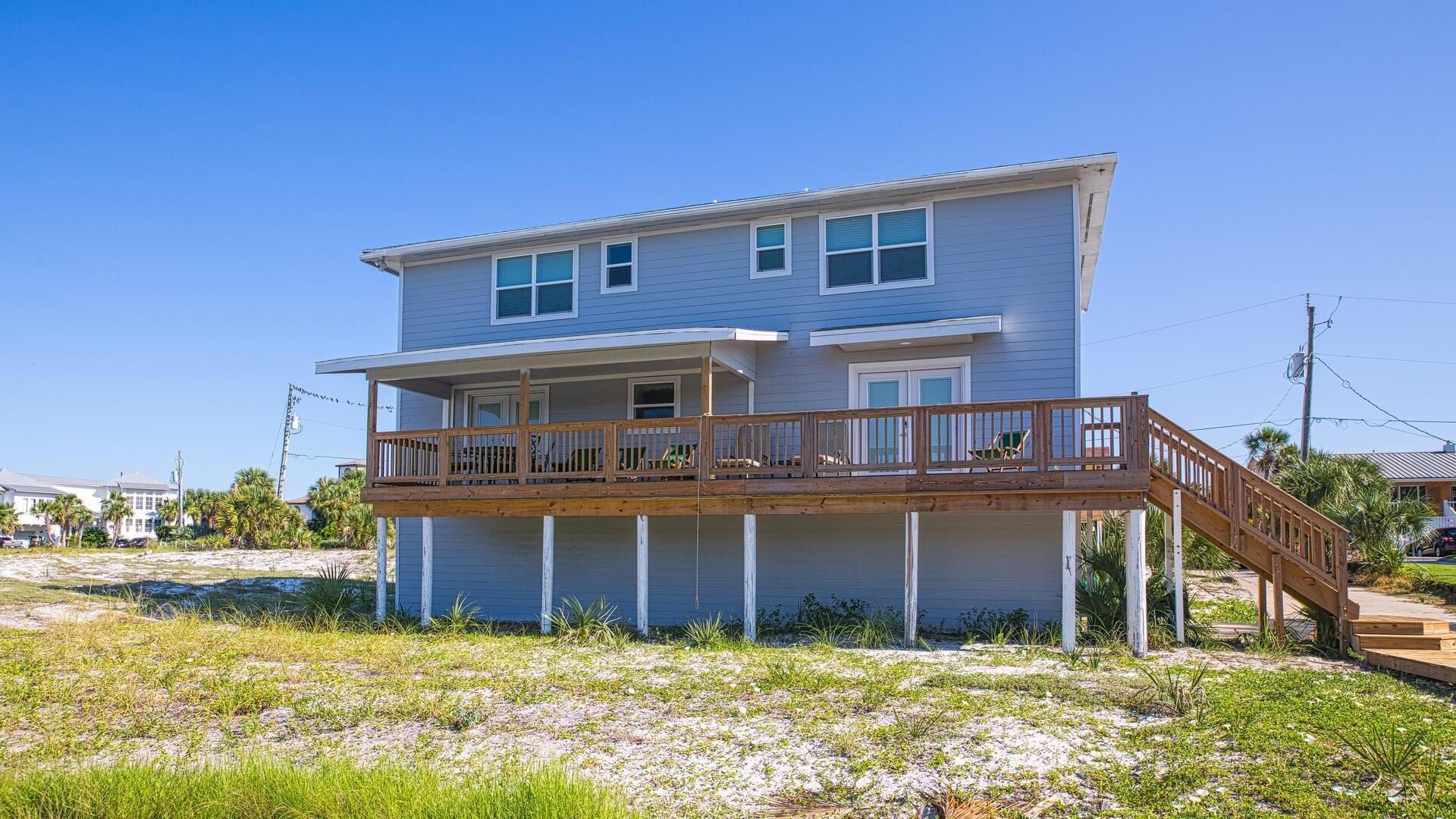 A two-story house with a wooden deck and a small staircase leading to the second floor.