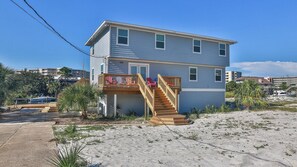 A two-story house with a wooden deck and a small staircase leading to a balcony. - The Back Porch (Destin)