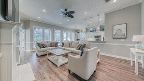 Un salón espacioso con un sofá modular, una mesa de centro y un comedor, con una cocina al fondo.