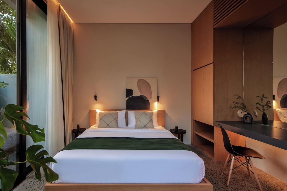 Une chambre à coucher moderne avec un lit, des tables de chevet, un bureau et une chaise.