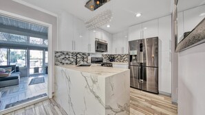 Una cocina moderna con una isla de mármol, electrodomésticos de acero inoxidable y un salpicadero con diseño.