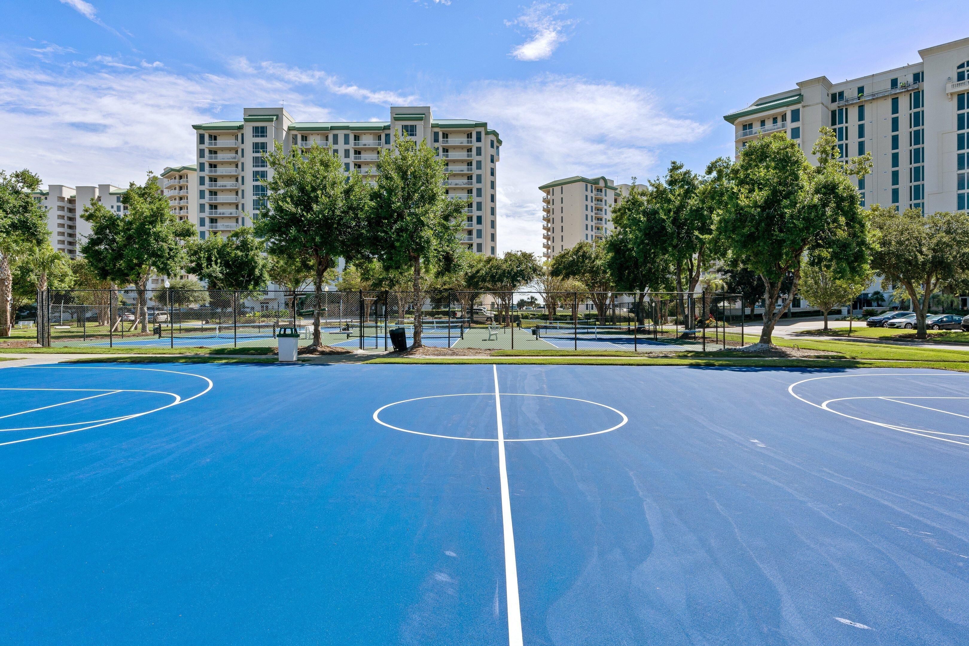An outdoor basketball court surrounded by trees and buildings.