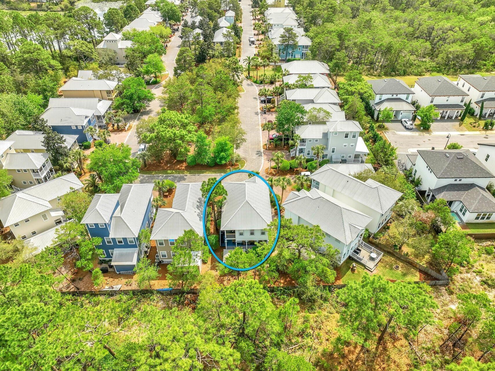 A residential area with multiple houses, a central road, and surrounding greenery.