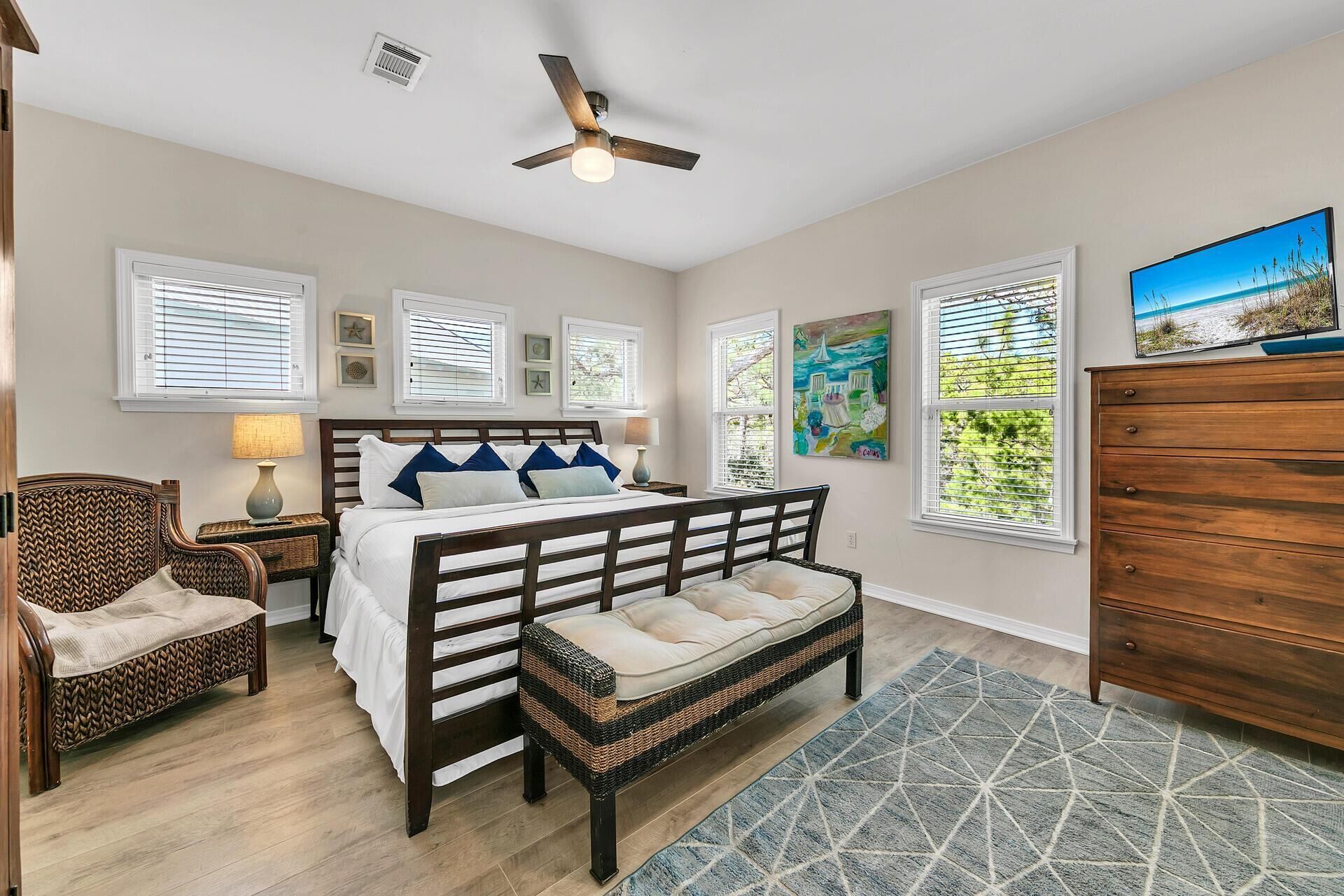 A bedroom with a bed, a bench, a dresser, and a ceiling fan.
