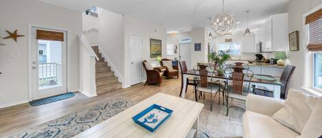 A spacious living area with a staircase, dining table, and chairs.