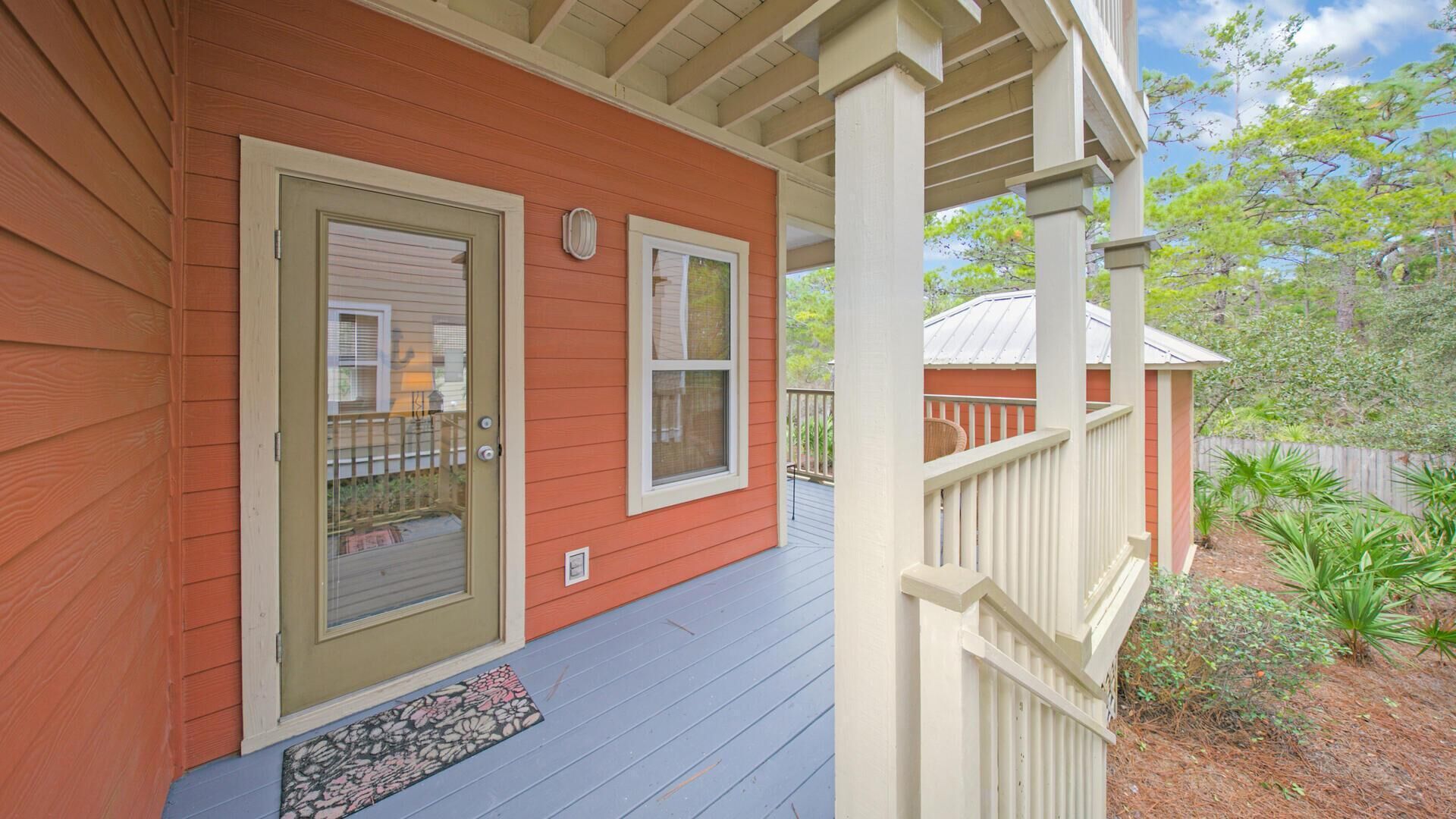 A house with a red exterior, a front door, and a covered porch with a railing.