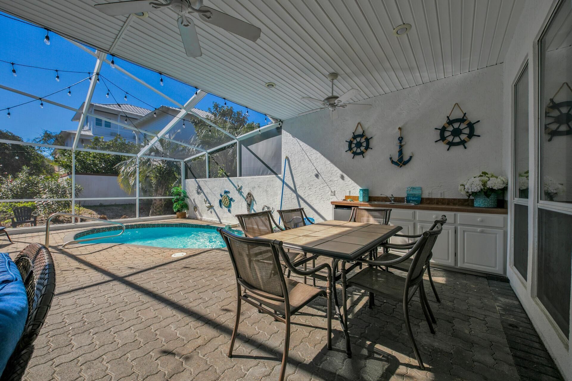 A covered outdoor area with a pool, seating, and nautical decor.