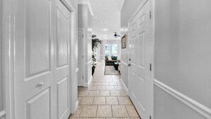 A hallway with white doors, a tiled floor, and a ceiling fan. - Destiny Casa (Destin)