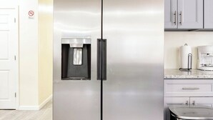 A modern kitchen with a stainless steel refrigerator, a water dispenser, and a coffee maker on the countertop.