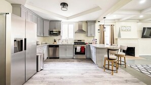 A modern kitchen with grey cabinets, stainless steel appliances, and a central island with bar stools.