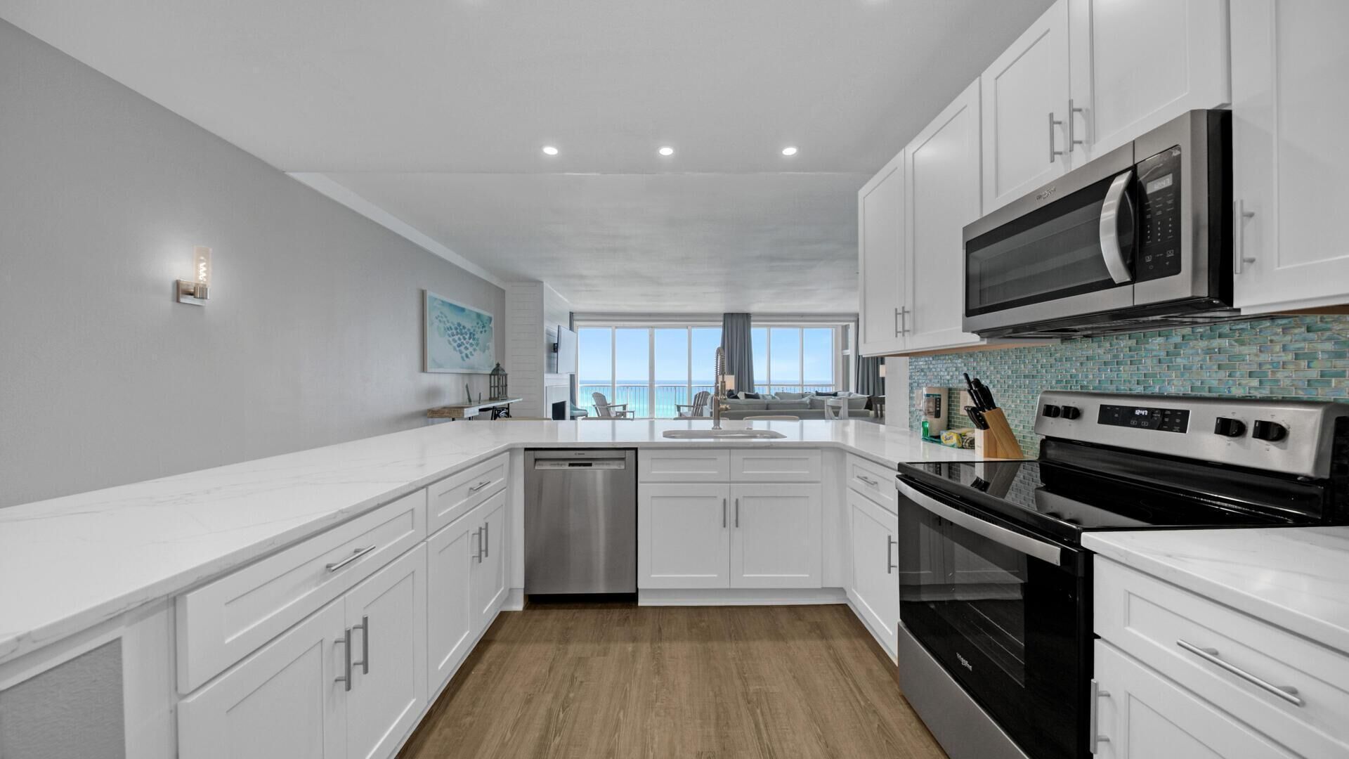 A modern kitchen with white cabinetry, stainless steel appliances, and a view to the outside.