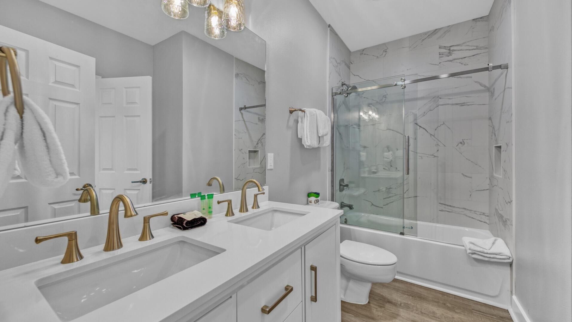 A modern bathroom with two sinks, a toilet, and a glass-enclosed shower.