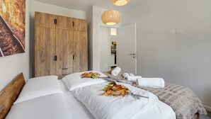 A hotel room with a wooden wardrobe, a bed with white linens, a decorative leaf arrangement, and two woven pendant lights. - Appartamento 30 Nodi 2 Torbole-Arco, Arco, Italy (Arco)